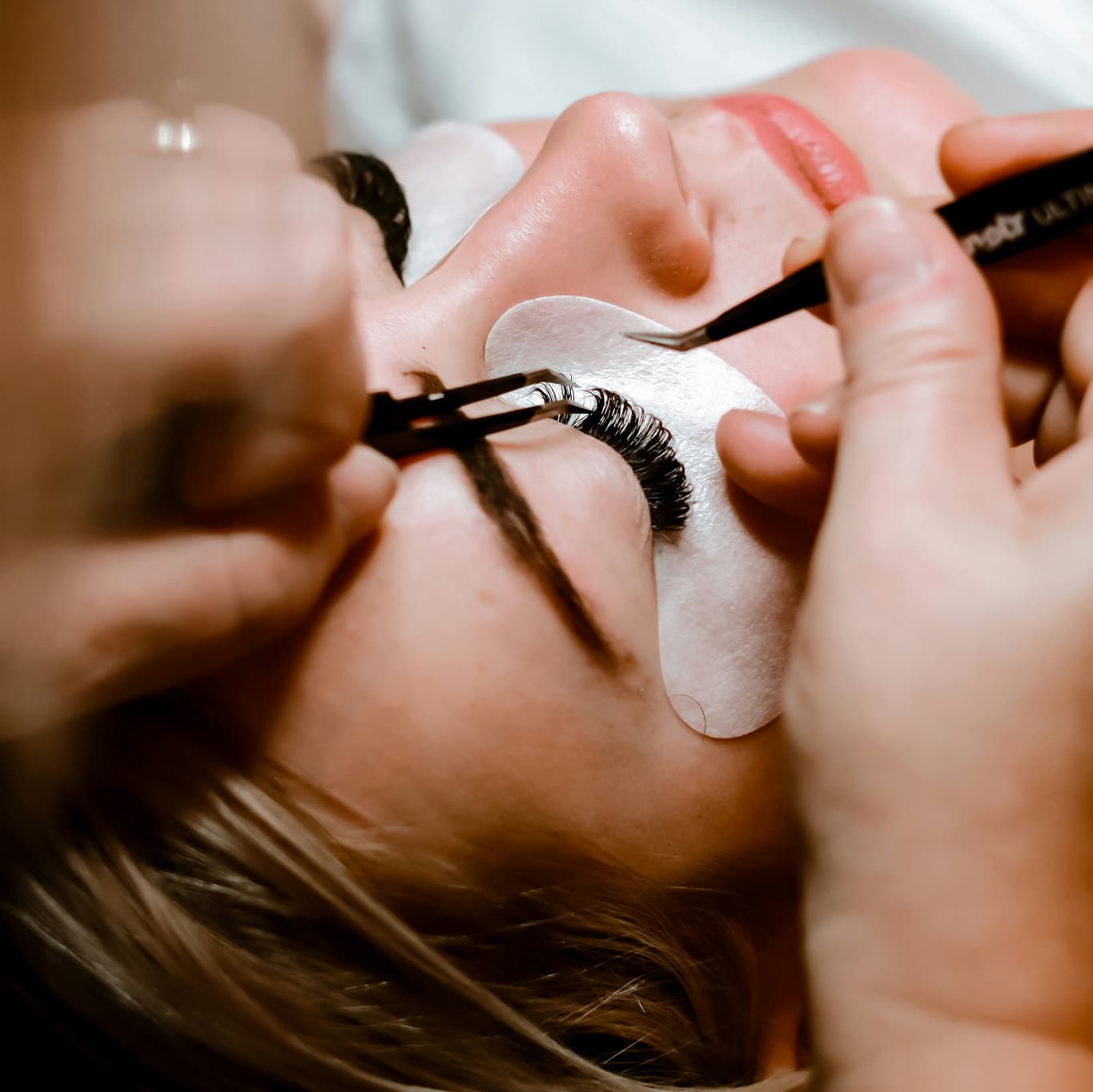 A lash technician applying extensions to a client